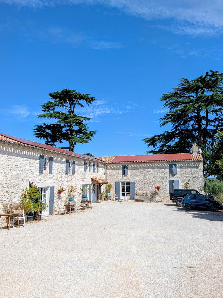 The gravel courtyard and stone buildings of The Old Presbytery under a bright blue sky